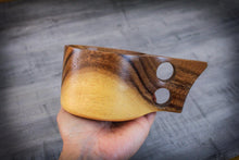 Load image into Gallery viewer, Hand hält eine skandinavische Kuksa-Tasse aus Akazienholz mit zwei runden Grifföffnungen – rustikaler, handgefertigter Holzmug für den Outdoor-Gebrauch
