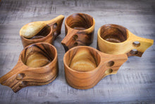 Laden des Bilds im Galerie-Viewer, Handgefertigte Kuksa-Becher aus Akazienholz im skandinavischen Design, fünf natürliche Holztassen mit ergonomischem Henkel, dekorativ auf Holztisch angeordnet.