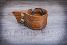 Laden des Bilds im Galerie-Viewer, Ein einzelner handgefertigter Kuksa-Becher aus Akazienholz im skandinavischen Design mit ergonomischem Doppelgriff, dekorativ auf grauem Holztisch platziert.