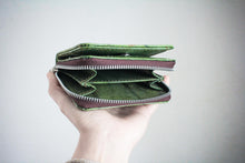 Laden des Bilds im Galerie-Viewer, Eine Hand hält ein kleines, geöffnetes Portemonnaie in Grün, hergestellt aus veganem Blattleder. Die inneren Kartenfächer und der Druckknopfverschluss sind sichtbar vor einem hellen Hintergrund.
A hand holding open a small green vegan wallet made from leaf leather. The interior card slots and snap button closure are visible against a plain light background.
Open green wallet with a brown zip and interior. The wallet is revealing multiple compartments. The zip color is silver.
