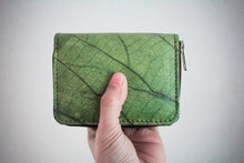 Laden des Bilds im Galerie-Viewer, Nachhaltiges, veganes Portemonnaie aus grünem Blattmaterial mit Reißverschluss, frontal in einer Hand vor weißem Hintergrund gehalten – umweltfreundliche Geldbörse für Damen und Herren.
Sustainable vegan wallet made from green leaf material with zipper, held front-facing in a hand against a white background – eco-friendly unisex purse.
