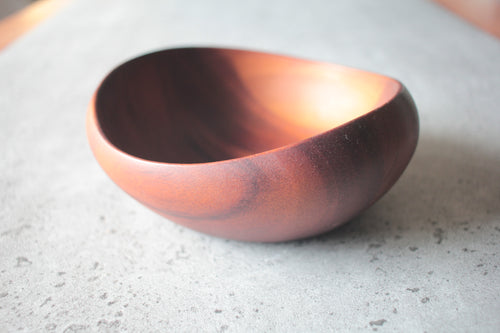 Round wooden bowl made of dark wood, handcrafted with natural grain