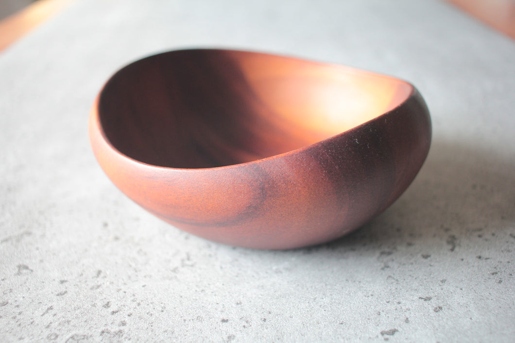 Round wooden bowl made of dark wood, handcrafted with natural grain