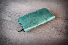 Laden des Bilds im Galerie-Viewer, Türkises veganes Portemonnaie aus recycelten Blättern auf einem Holztisch, nachhaltige Damen-Geldbörse mit Reißverschluss.

Turquoise vegan wallet made from recycled leaves on a wooden table, sustainable ladies zip-around purse.
