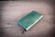 Laden des Bilds im Galerie-Viewer, Turquoise vegan wallet made from recycled leaves on a wooden table, sustainable ladies zip-around purse.

Türkises veganes Portemonnaie aus recycelten Blättern auf einem Holztisch, nachhaltige Damen-Geldbörse mit Reißverschluss.

