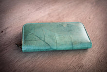 Laden des Bilds im Galerie-Viewer, Close-up of a turquoise wallet made from recycled leaves showing the leaf texture and zipper.

Detailaufnahme eines türkisen Portemonnaies aus recycelten Blättern mit sichtbarer Blattstruktur und Reißverschluss.
