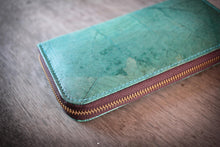 Laden des Bilds im Galerie-Viewer, Nahaufnahme einer nachhaltigen, veganen Geldbörse in Türkis, hergestellt aus recycelten Blättern. Der goldene Reißverschluss und die sichtbare Blattstruktur sind im Fokus.

Close-up of a sustainable, vegan turquoise wallet made from recycled leaves, focusing on the golden zipper and the visible leaf texture and stitching.
