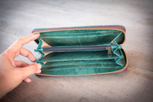 Laden des Bilds im Galerie-Viewer, Innenansicht der geöffneten, veganen Geldbörse in Türkis, hergestellt aus recycelten Blättern. Eine Hand hält die Brieftasche, die mehrere Fächer und ein Münzfach mit Reißverschluss zeigt.

Interior view of the open, vegan turquoise wallet made from recycled leaves. A hand holds the wallet, showing multiple card slots and a zippered coin pocket.
