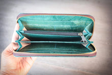 Laden des Bilds im Galerie-Viewer, Interior view of the open, vegan turquoise wallet made from recycled leaves. A hand holds the wallet, showing multiple card slots and a zippered coin pocket.

Innenansicht der geöffneten, veganen Geldbörse in Türkis, hergestellt aus recycelten Blättern. Eine Hand hält die Brieftasche, die mehrere Fächer und ein Münzfach mit Reißverschluss zeigt.
