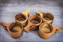 Laden des Bilds im Galerie-Viewer, Handgefertigte Kuksa-Becher aus Akazienholz im skandinavischen Design, fünf natürliche Holztassen mit ergonomischem Henkel, dekorativ auf Holztisch angeordnet.
