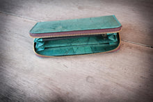 Laden des Bilds im Galerie-Viewer, Eine Hand präsentiert die geöffnete, handgefertigte Geldbörse in Türkis, hergestellt aus recycelten Blättern. Die Innenfächer und das zentrale Reißverschlussfach sind sichtbar.

A hand presenting the open, handmade turquoise wallet, made from recycled leaves. The interior compartments and central zippered pocket are clearly visible.
