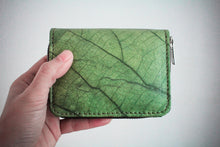Laden des Bilds im Galerie-Viewer, Nachhaltiges, veganes Portemonnaie aus grünem Blattmaterial mit Reißverschluss, seitlich in einer Hand vor weißem Hintergrund gehalten – umweltfreundliche Geldbörse für Damen und Herren.

Sustainable vegan wallet made from green leaf material with zipper, held sideways in a hand against a white background – eco-friendly unisex purse.
