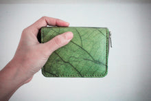 Laden des Bilds im Galerie-Viewer, Nachhaltiges, veganes Portemonnaie aus grünem Blattmaterial mit Reißverschluss, seitlich in einer Hand vor weißem Hintergrund gehalten – umweltfreundliche Geldbörse für Damen und Herren.

Sustainable vegan wallet made from green leaf material with zipper, held sideways in a hand against a white background – eco-friendly unisex purse.
