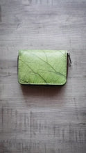 Laden und Abspielen von Videos im Galerie-Viewer, Dieses Video zeigt das grüne, vegane Portemonnaie aus recycelten Blättern im Detail. Es demonstriert das Aufklappen der Kartenfächer mit Druckknopf sowie das Öffnen des separaten Münzfachs mit Reißverschluss. Am Ende ist ein Vergleich mit der türkisen Version zu sehen.

This video details the green vegan wallet made from recycled leaves. It demonstrates opening the snap-button card slots and the separate zippered coin pocket. The video concludes with a side-by-side view next to the turquoise version.

