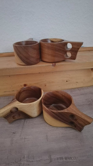 Handcrafted Kuksa mugs made from acacia wood in Scandinavian design, five natural wooden cups with ergonomic handles, artfully arranged on a wooden table.
Handgefertigte Kuksa-Becher aus Akazienholz im skandinavischen Design, fünf natürliche Holztassen mit ergonomischem Henkel, dekorativ auf Holztisch angeordnet.
